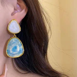 Detailed close-up of vintage resin drop earrings with blue and white marble patterns.