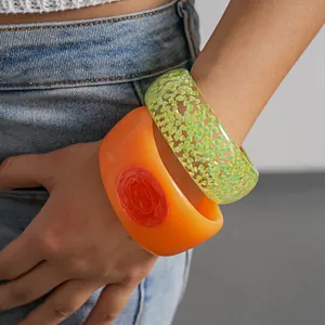 Detailed close-up of vibrant orange and neon green resin bangles worn on the wrist