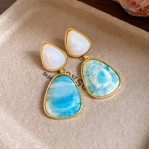 Close-up of vintage resin drop earrings with blue marble texture and gold frame