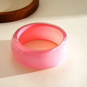 Macro view of a thick pink resin bangle bracelet featuring a subtle glitter shimmer finish