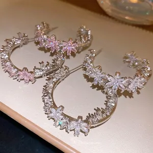 Elegant C-shaped hoop earrings featuring shimmering zircon flowers and silver pins.