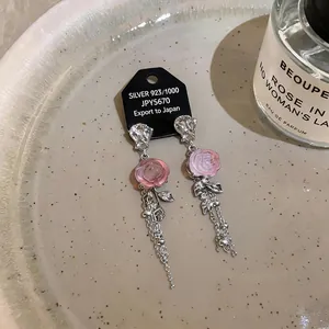 Primo piano di orecchini a fiore in resina rosa con nappe argentate