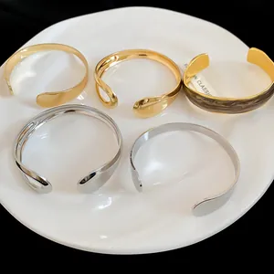Close-up detail of irregular metal open cuff bracelets in gold and silver finishes