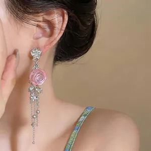 Dettaglio orecchini a rosa in resina rosa con lunghe catene a nappa in argento