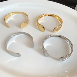 Four irregular minimalist metal open cuff bracelets in polished gold and silver finishes