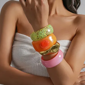 Detail of colorful chunky resin and gold geometric bracelets on a stylish woman's wrist