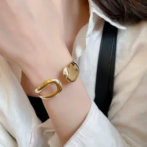 Close-up detail of a minimalist gold irregular metal open cuff bangle worn on a wrist