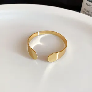 High-quality close-up of a minimalist gold open cuff bracelet with smooth polished finish