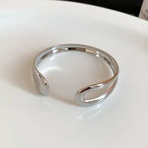 Detailed macro view of irregular polished silver open metal bangle with minimalist design