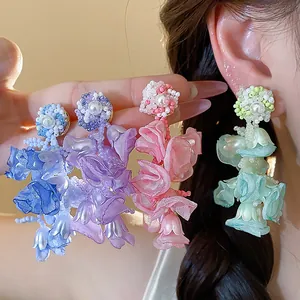 Close-up detail of colorful chiffon flower earrings with pearls and delicate beadwork.