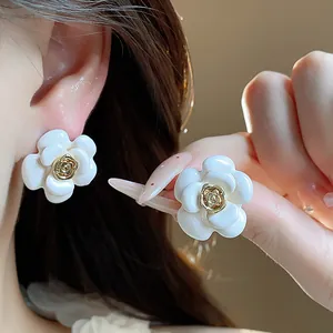 Gros plan de boucles d'oreilles fleurs blanches plaquées or 18 carats avec émail.
