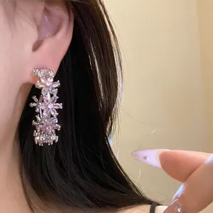 Detailed close-up view of elegant pink zircon flower C-shaped drop earrings worn on ear