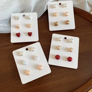 Detailed macro view of geometric pearl and heart stud earring sets on elegant white cards