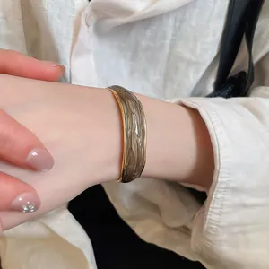Detailed view of irregular gold-rimmed cuff bracelet with a unique brown textured inlay.