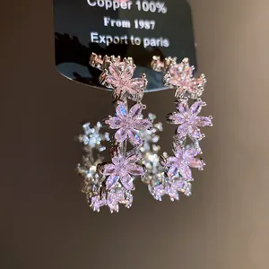 Macro view of pink zircon flower C-shaped earrings with brilliant sparkling details.