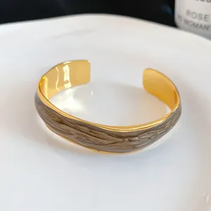 Detail showing the elegant gold open cuff bracelet with unique brown marbled enamel inlay