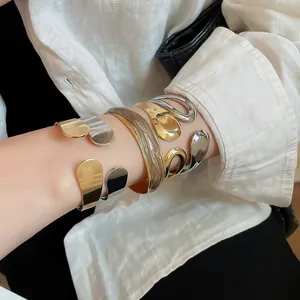 Detailed view of multiple layered irregular metal cuff bracelets in gold and silver finish