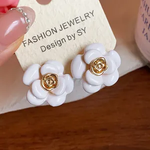 Gros plan sur des boucles d'oreilles camélia en émail blanc avec centre plaqué or 18 carats