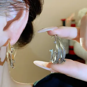 Detailed macro view of 18k gold-plated C-shaped earrings with sparkling zircon stones