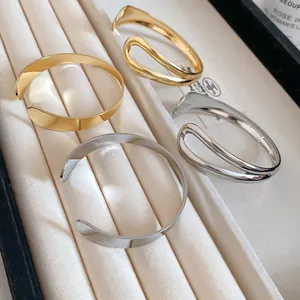 Close-up of minimalist irregular metal open cuff bracelets in gold and silver tones