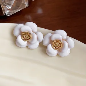Détail rapproché de boucles d'oreilles camélia blanc plaqué or 18 carats avec émail