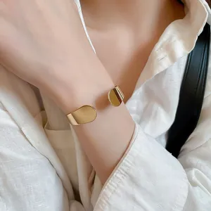 Close-up of a minimalist gold irregular metal open cuff bracelet on female wrist