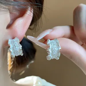 Detailaufnahme von eleganten silbernen C-förmigen Ohrringen mit glitzernden Zirkonia