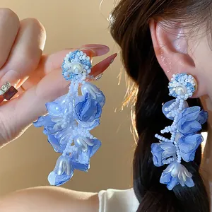 Detailed macro shot of elegant blue chiffon flower earrings with pearls and beads