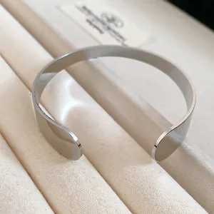 Macro detail shot of a minimalist silver metal open cuff bracelet on jewelry tray.