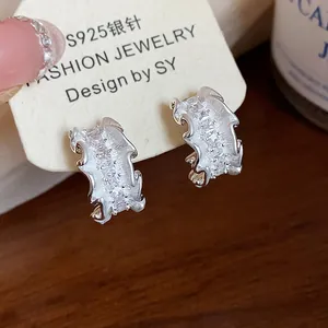 Detail von silbernen S925 C-Ohrringen mit Zirkonia und zerknitterter Textur