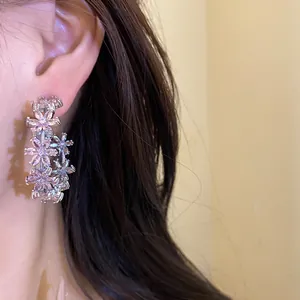 Close-up view of elegant silver flower C-shaped zircon earrings worn on the ear