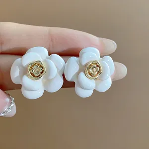 Vue détaillée de boucles d'oreilles camélia blanc avec centre plaqué or 18 carats.