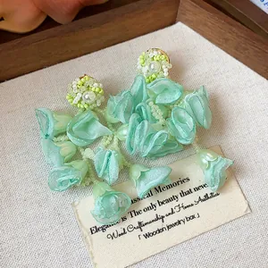 Close-up of mint green chiffon flower earrings with pearls and bead embroidery detail