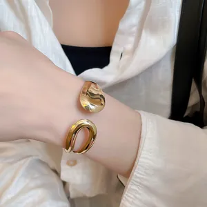 Close-up detail of a minimalist irregular gold open cuff bracelet worn on the wrist