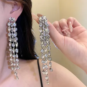 Close-up of sparkling long tassel rhinestone earrings on ear for a glamorous look