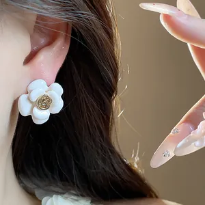 Gros plan sur une boucle d'oreille camélia blanche dorée à l'or 18K