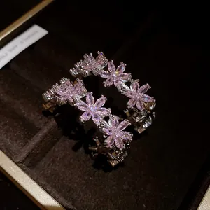 Macro detail of elegant C-shaped earrings featuring sparkling pink zircon flowers