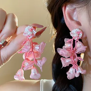 Macro detail view of pink chiffon flower earrings with pearl and beaded tassels.
