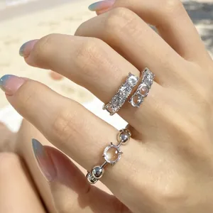 Vista dettagliata di eleganti anelli aperti in argento con zirconi e perle di resina