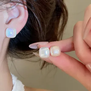 Detail view of elegant iridescent square stud earrings with a shiny pearl finish
