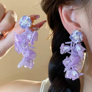 Detailed view of purple chiffon flower earrings with pearls and bead strings