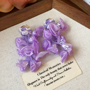 Close-up detail of handmade purple chiffon flower earrings with delicate beadwork