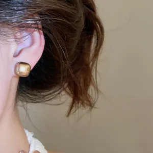 Detailed macro view of a vintage gold geometric square stud earring worn on ear