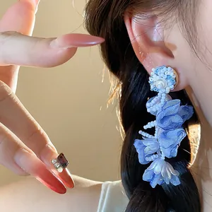 Close-up detail of elegant blue chiffon flower earrings with pearls for vacation style