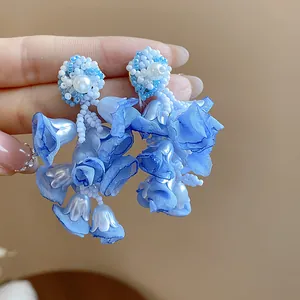 Close-up detail showing blue chiffon flower petals and delicate beadwork on earrings.
