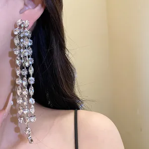 Detailed view of sparkly silver needle earrings with long rhinestone tassels.