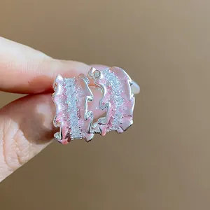 Makro-Detail von rosa emaillierten C-förmigen Ohrringen mit glänzenden Zirkonia