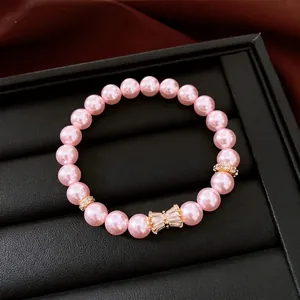 Elegante bracciale di perle rosa con fiocco di zirconi su un vassoio per gioielli nero.