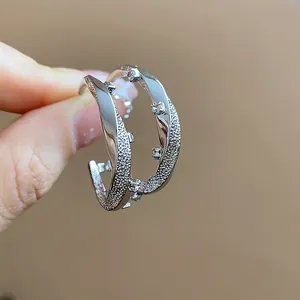 Macro view of C-shaped earrings with textured silver finish and zircon accents