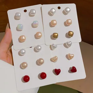 Close-up of geometric heart and pearl stud earring sets on white display cards